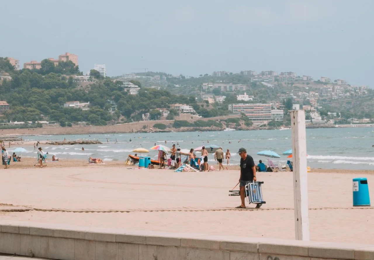 Turismo internacional en la costa española ALT Text: Turistas disfrutan de una playa mediterránea de Benidorm, España, durante sus vacaciones.